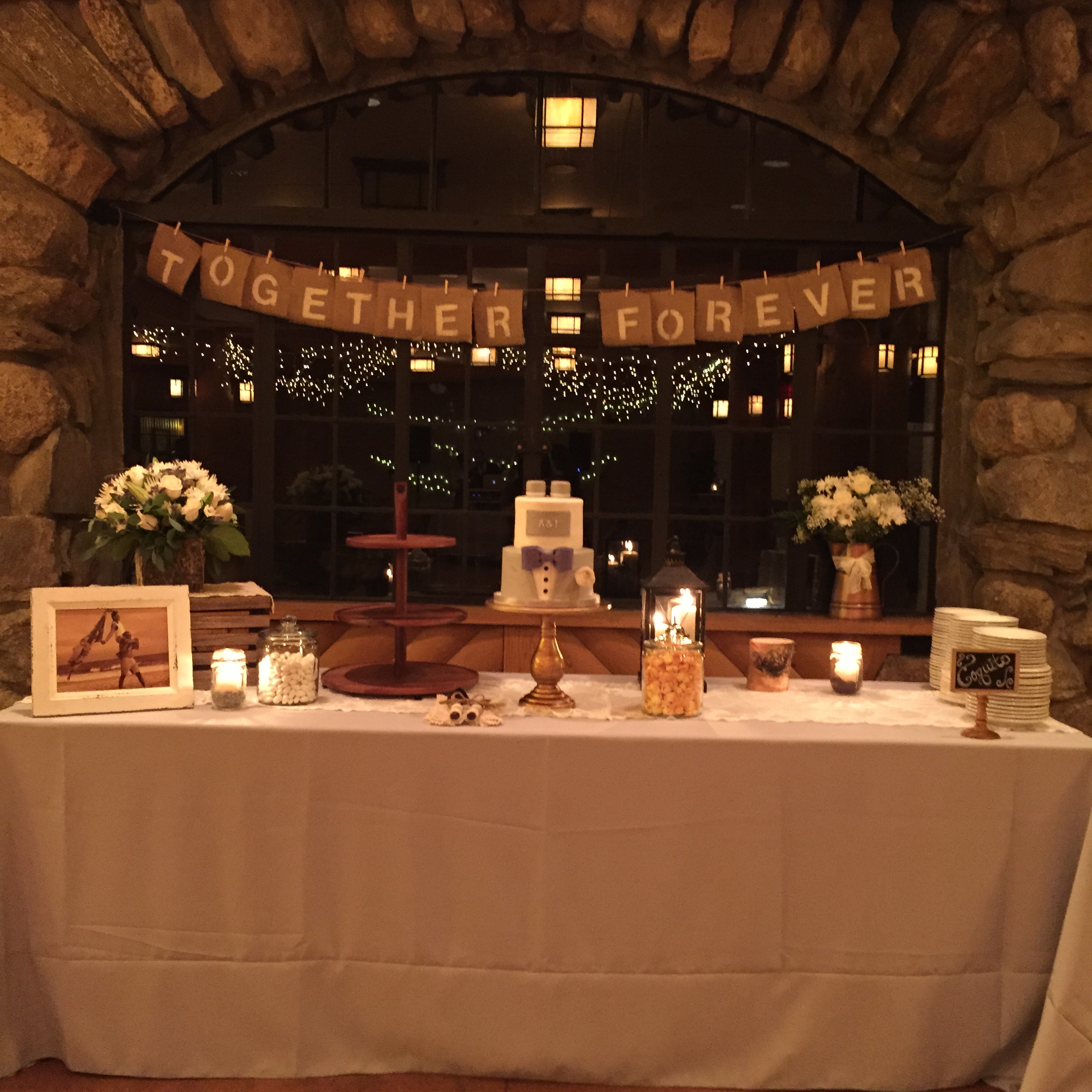 A wedding cake, plates, and an image of the newlywed couple sitting on a long rectangular table